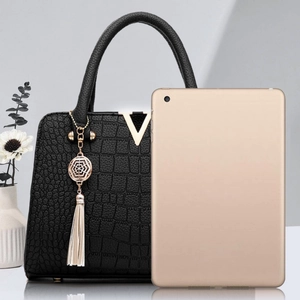 Sac à main noir à motif crocodile élégant avec détail en V doré et pendentif à pompon blanc