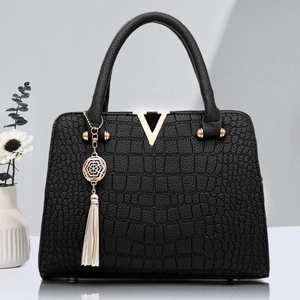 Sac à main élégant noir motif crocodile avec logo V doré et pompon sur fond minimaliste