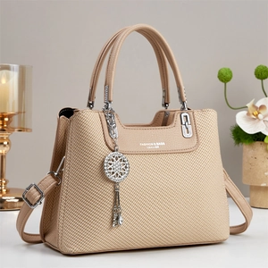 Beige woven texture handbag with shoulder strap and dreamcatcher pendant detail