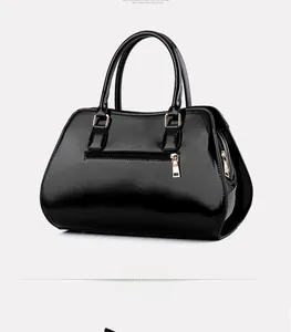 Detailed back view of a black patent leather handbag with a sleek rose gold zipper pocket