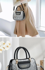 Detail of silver snakeskin tote with gold logo and cute cat charm on black handles