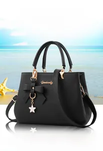Detail of black lychee grain leather bag with golden bow and star charms decoration