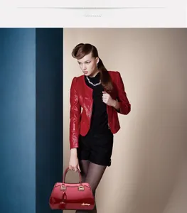 Detail view of red glossy patent leather handbag with gold buckle and heart charm