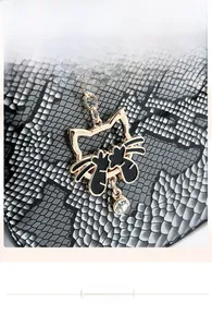Detail of a golden cat pendant with rhinestone on black and white snakeskin texture