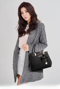 Detail of black lychee grain leather handbag with bow ribbon and gold logo accent