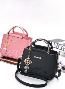 Detail of pink and black lychee leather handbags with 3D rose embroidery and gold rings