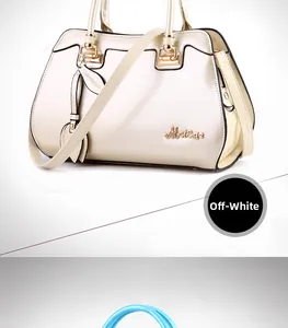 Detail of white patent leather handbag with gold hardware and leaf-shaped pendant charm