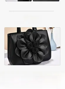 Close-up of elegant black handbag featuring a large handcrafted 3D floral decoration