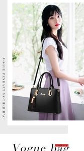 Detail of black leather mother bag with golden hardware and decorative tassel pendant