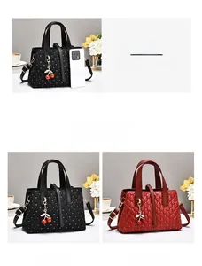 Detail der gesteppten Beuteltasche in Schwarz und Rot mit Kirsch-Anhängern