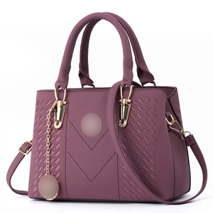 Detail of deep purple faux leather handbag with braided V-shape pattern and gold hardware