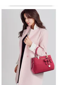 Close-up of rose red handbag with lychee texture, bow decoration and gold star charm