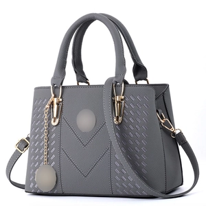 Close-up of grey leather handbag featuring V-quilted texture and gold hardware