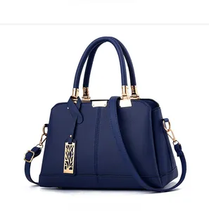 Dettaglio borsa in pelle blu zaffiro con finiture dorate e ciondolo a forma di foglia