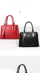 Detail of red and black matte leather tote bags with cat tassels and golden metal hardware