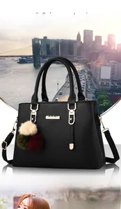 Close-up of black lychee texture leather bag with gold hardware and colorful fur pompom