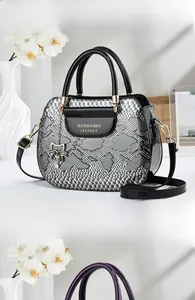 Detail of snake pattern leather texture and cat pendant on luxury black tote bag