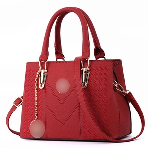 Detail of red faux leather handbag featuring V-shaped stitching and woven side textures