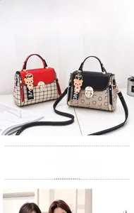 Detail of red plaid and black lettered crossbody bags with golden twist lock and bear charms
