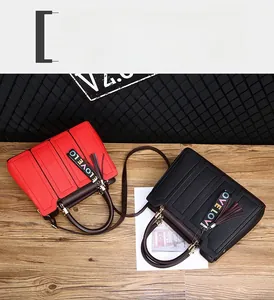 Détail des sacs à main en cuir grainé rouge et noir avec pendentifs LOVE à franges