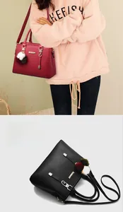 Close-up of litchi grain faux leather handbag featuring a fluffy pompom charm and shoulder strap