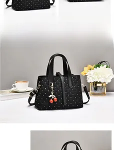 Detailansicht der schwarzen gesteppten Handtasche mit Kirsch-Anhänger und Perlenstickerei