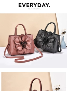 Close-up of leather handbag featuring large 3D flower decoration and detachable strap