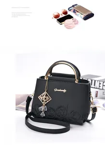 Detail of black leather handbag with rose embroidery, gold handles and metal logo tag