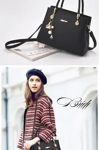 Detail of black lychee grain leather handbag with gold hardware and floral pearl pendant