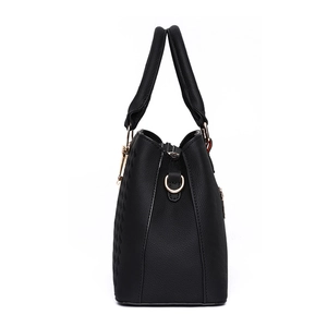 Side view of black pebble leather handbag with gold metal rings and double handles
