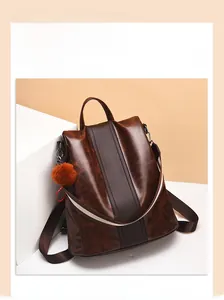 Detail of retro brown leather backpack with orange pompom and decorative stripe