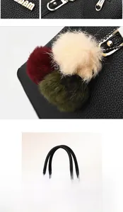Close-up of black litchi grain tote bag with gold logo and tricolor pompom charm