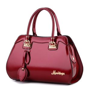 Glossy burgundy patent leather handbag with gold hardware and leaf pendant charm