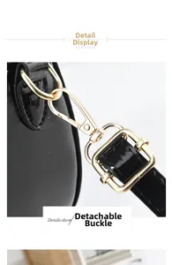 Macro shot of detachable light gold metal buckle on black patent leather shoulder bag