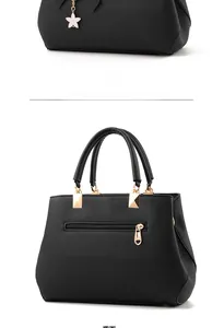 Detail of black lychee grain leather handbag with gold hardware and heart zipper puller