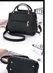 Detail of black pebbled leather crossbody bag with gold hardware and bottom protective studs