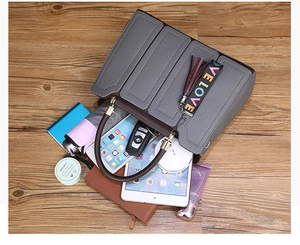 Sac à main gris en cuir grainé montrant sa grande capacité avec des objets du quotidien