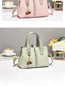 Detail der gesteppten Eimertasche mit Metallnieten und Kirschanhänger-Verzierungen