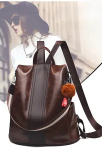 Detail of dark brown leather backpack with contrast stripes and plush charm on side