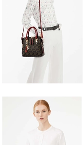 Close-up of monogram print detail and red handles on a dark brown crossbody handbag
