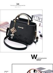 Close-up of black leather bag featuring 3D rose embroidery and gold ring handles