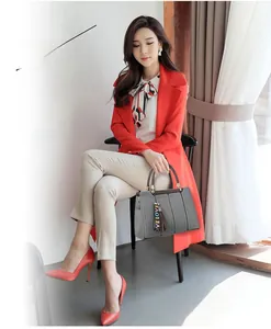 Détail du sac à main en cuir gris avec anses brunes et ruban LOVE sur manteau rouge