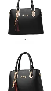 Close-up of black PU leather handbag with gold handle hardware and a cat tassel charm