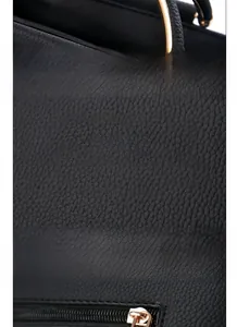 Detail of reinforced handles, golden logo plaque and zipper on black leather handbag