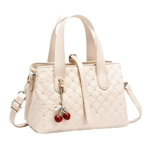 Elegant quilted cream bucket bag with star stitching and decorative cherry charm