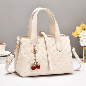 Gesteppte cremefarbene Handtasche mit Strassdetails und Kirsch-Anhänger in Lifestyle-Szene