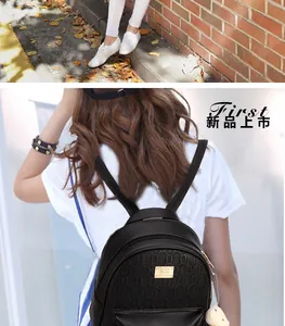Close-up of black backpack with geometric texture, gold hardware and plush bear charm