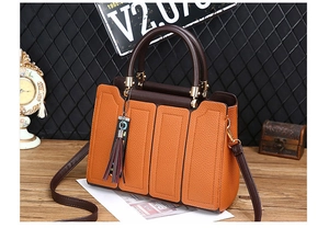 Détail du sac à main orange et marron en cuir grainé avec pompon décoratif élégant