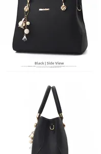 Detail of black pebbled leather handbag with gold hardware and floral pearl charm