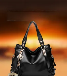 Close-up of black lychee grain leather handbag with gold hardware and tassel detail